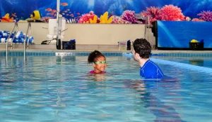 swimming instructor guiding young child
